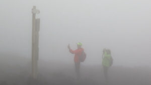 Two people in the mist, looking at a sign for directions