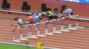 Professional hurdlers as they jump a hurdle at speed.