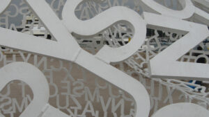 A mosaic of letters through which is a vague background of a boat