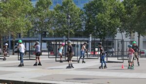 A group of people learning to rollerblade in a public square on a sunny day.