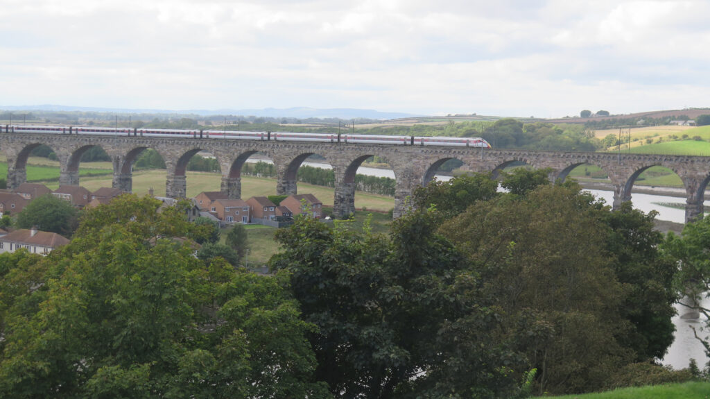 A train crossing a long viaduct style bridge over a vally.