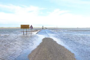 A road, blocked by the rising tide with warning signs not to continue