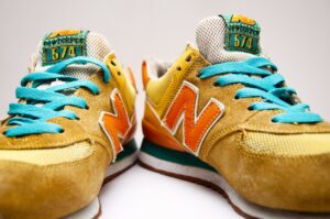 A new pair of sneakers, which have gold coloured uppers, turquoise laces and red lettering on the side
