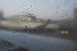 Raindrops on a window, with a background out of focus and grey