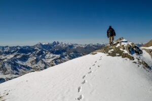 A person at the top of a snow-covered mountain.