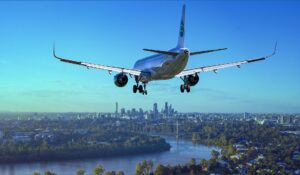 An aeroplane coming in to land, a cityscape in the background.