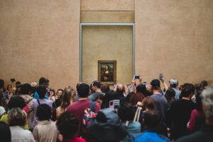 A crowd of people in the Louvre all looking at the Mona Lisa