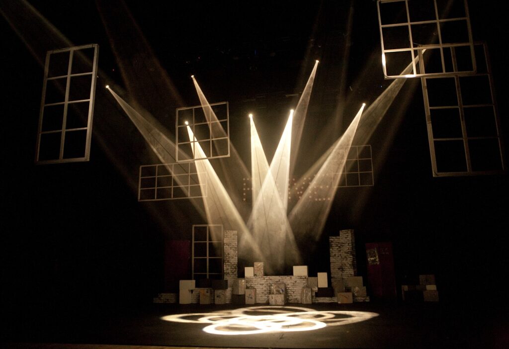 A stage, with scenery lit by multiple spotlights. The stage is set and the actors are yet to arrive