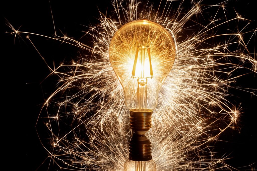 A lightbulb lit by electricity and with sparks coming from the bulb