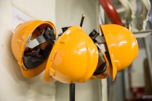 Three orange hardhats hanging on hooks. They are a sign of taking safety seriously.