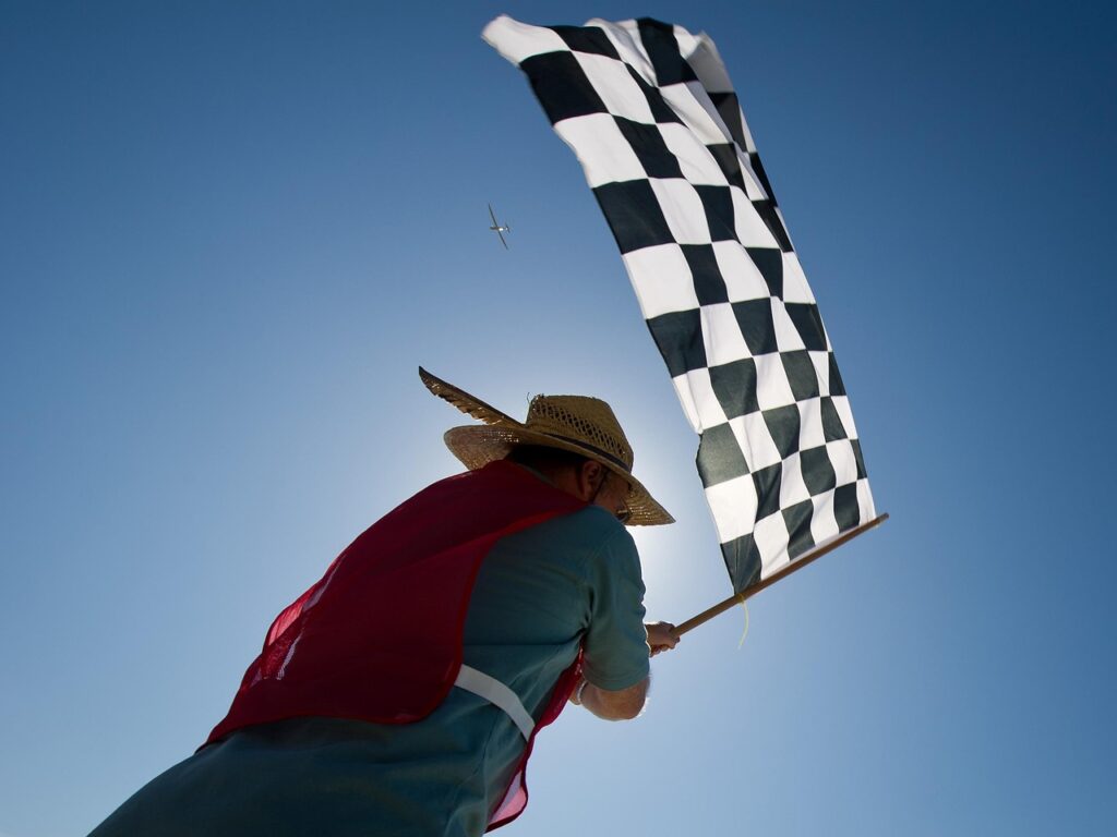 A person holding a chequered flag, which is fully extended in the breeze.