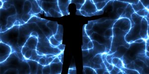 The silhouette of a person in front of a representation of human neurons, all brightly lit, showing great mental activity.
