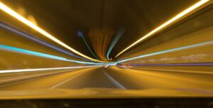 A blurred image of lights in a tunnel, with cars speeding through