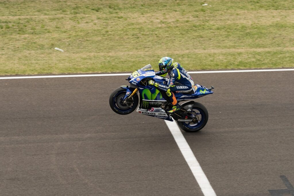 A motorcyclist is crossing the finish line of a race. They started with the end in mind and now they are there.