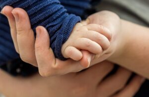 A picture of a baby's hand resting in the hand of an adult