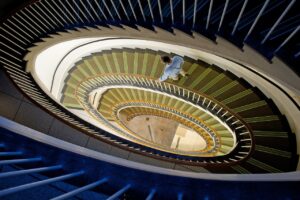 A long spiral staircase with a person walking down the stairs, one step at a time. It's all about regular steps to get you to where you want to be.