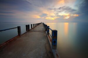 A jetty, stretching out over calm water to the horizon