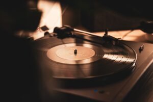 Close-up of a vinyl record spinning on a turntable under warm studio lighting, tonearm nearby.